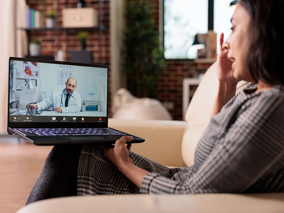 Una paciente accede a su consulta médica desde casa mediante telemedicina, destacando cómo la tecnología acerca el cuidado sin salir del hogar.
